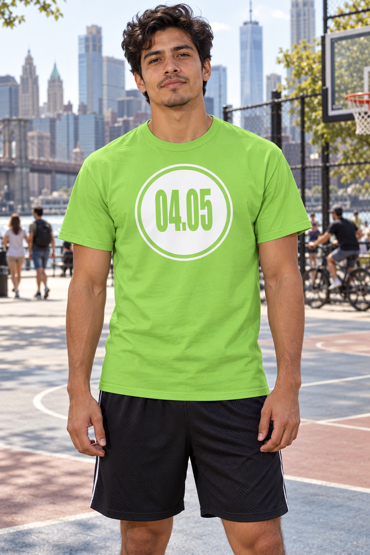 AI-generated Latino man age 27, tan skin, lean athletic build, dark wavy hair wearing Men’s 04.05 Bordered Circle Classic Tee — Lime; busy city basketball court promenade with skyline, pedestrians and cyclists