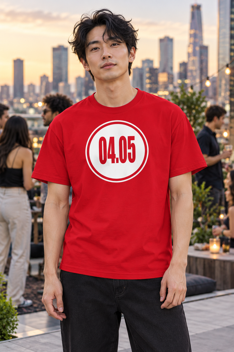 AI-generated East Asian man age 28, light skin, slender build, tousled black hair wearing Men’s 04.05 Bordered Circle Classic Tee — Red; busy downtown rooftop gathering with skyline and people softly blurred behind