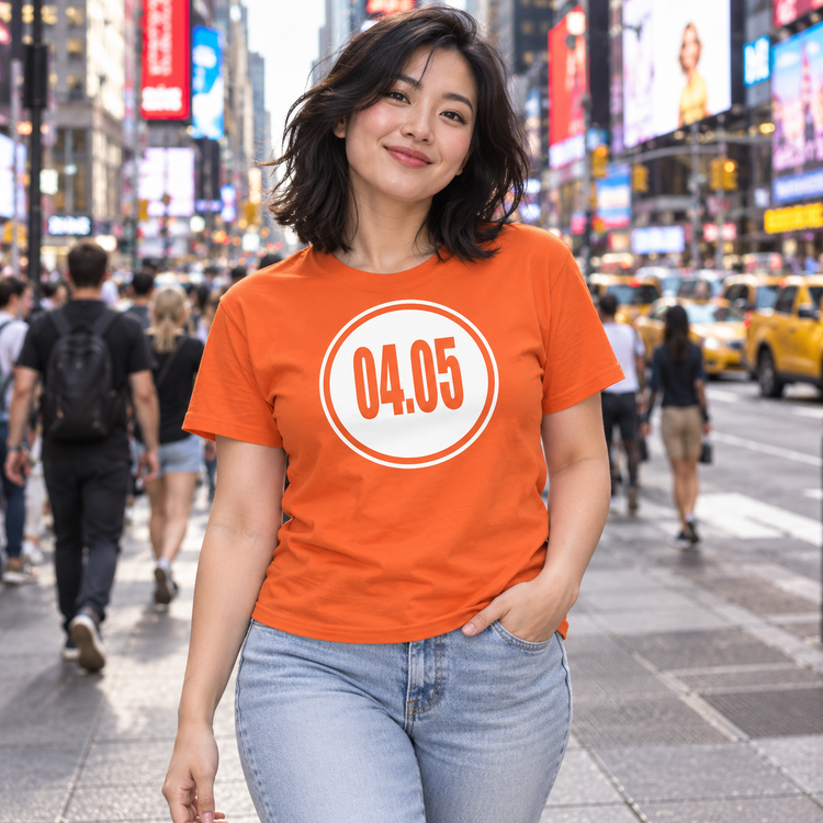 AI-generated model in her 20s wearing the orange 04.05 circle tee on a busy downtown sidewalk