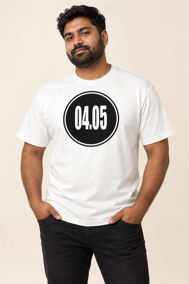 AI-generated South Asian man age 33, medium brown skin, stocky build, short dark hair and beard wearing Men’s 04.05 Bordered Circle Classic Tee — White; clean warm ivory studio